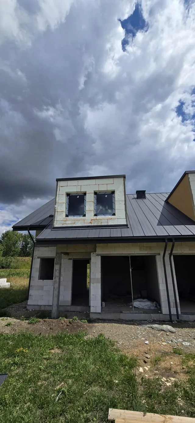 Lukarna ocieplona płytami styropianu z zamontowanymi oknami, poniżej podcień wejścia i otwory parteru