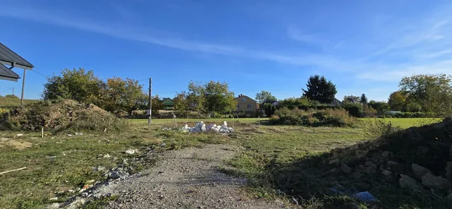 Teren pod kolejne budynki z palikami geodezyjnymi i stertą resztek bloczków